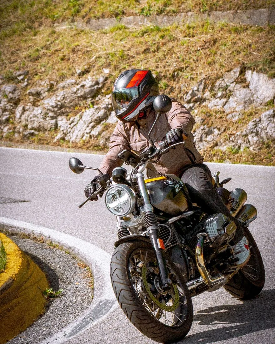 Benito Condemi de Felice in moto in una curva di montagna, con casco e giacca